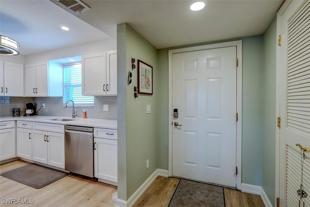 kitchen featuring dishwasher, sink, decorative backsplash, light hardwood / wood-style floors, and white cabinetry