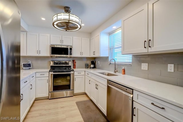 kitchen featuring appliances with stainless steel finishes, light hardwood / wood-style floors, white cabinetry, and sink