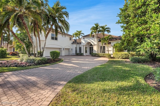 mediterranean / spanish house featuring a garage and a front lawn