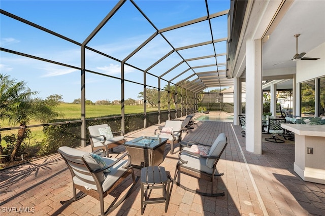 view of patio with a fire pit, ceiling fan, and a lanai