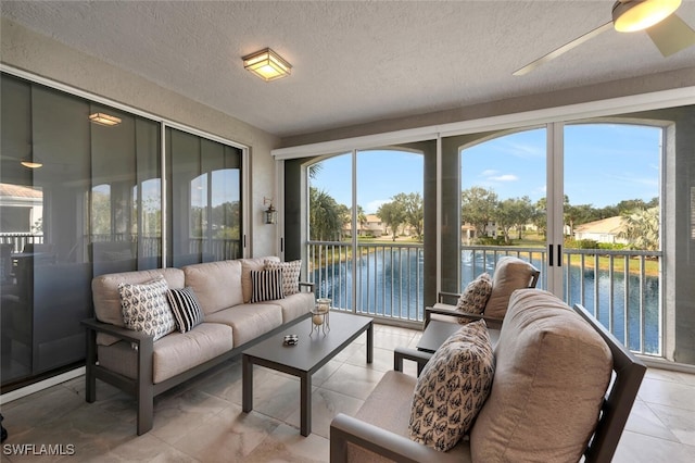 sunroom featuring ceiling fan, plenty of natural light, and a water view