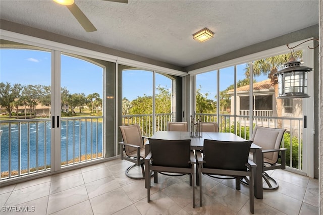 sunroom / solarium with ceiling fan and a water view