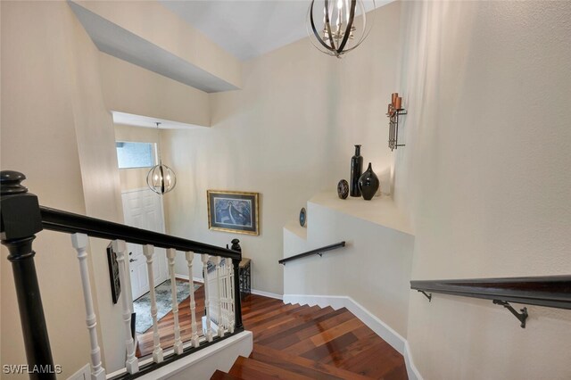 stairway with hardwood / wood-style flooring and a notable chandelier