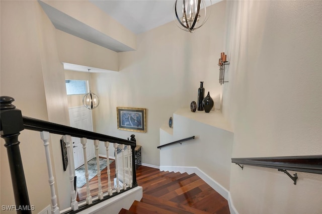 stairs with a notable chandelier, baseboards, and wood finished floors