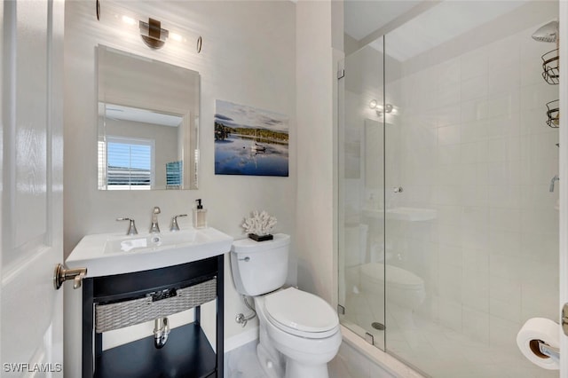 bathroom with toilet, a stall shower, baseboards, and vanity