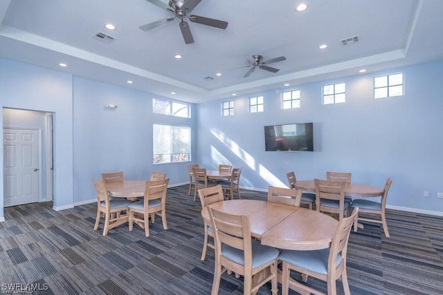 dining space featuring carpet floors, visible vents, a raised ceiling, and a wealth of natural light