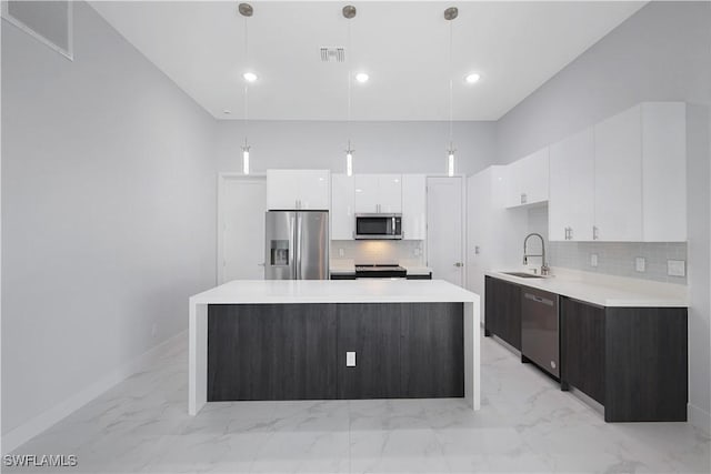 kitchen with white cabinetry, a kitchen island, hanging light fixtures, and appliances with stainless steel finishes