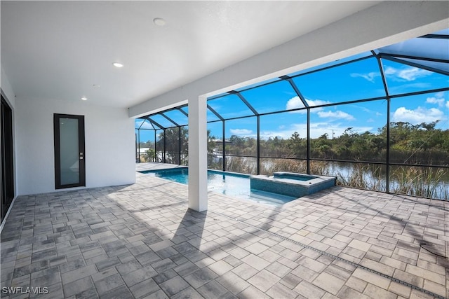 view of pool with an in ground hot tub, a patio, a water view, and glass enclosure