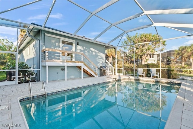 view of pool featuring a patio, glass enclosure, and grilling area