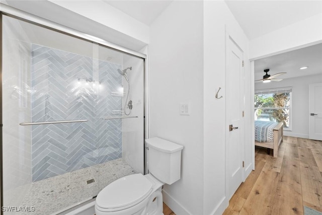 bathroom with hardwood / wood-style floors, toilet, an enclosed shower, and ceiling fan