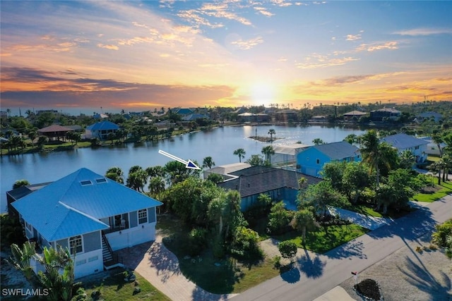 aerial view at dusk featuring a water view