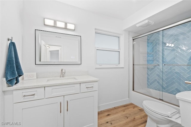 full bathroom featuring hardwood / wood-style floors, vanity, toilet, and shower / bath combination with glass door