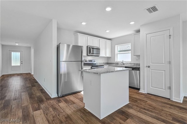 kitchen featuring a center island, stainless steel appliances, white cabinetry, and dark wood-type flooring