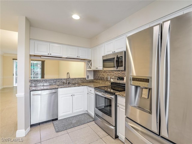 kitchen featuring white cabinets, sink, dark stone countertops, light tile patterned floors, and stainless steel appliances