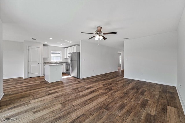 unfurnished living room featuring ceiling fan and dark wood-type flooring