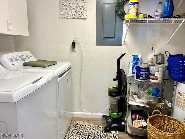 laundry area with wood finished floors, baseboards, independent washer and dryer, cabinet space, and electric panel