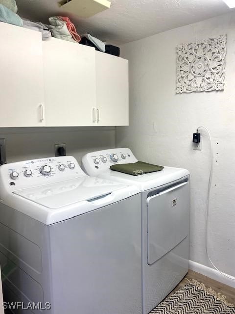 laundry area featuring independent washer and dryer, cabinets, hardwood / wood-style floors, and a textured ceiling