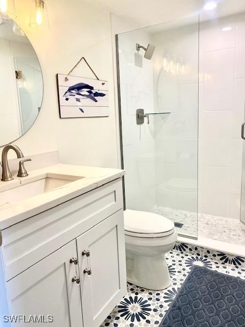 bathroom featuring tiled shower, vanity, toilet, and tile patterned floors