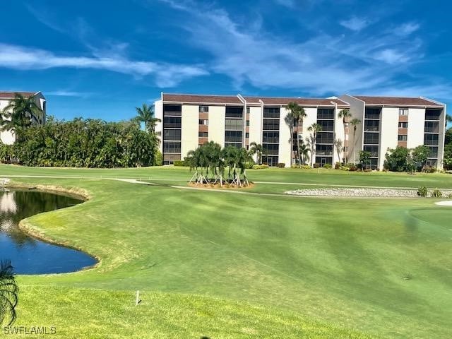 view of community with view of golf course, a water view, and a yard