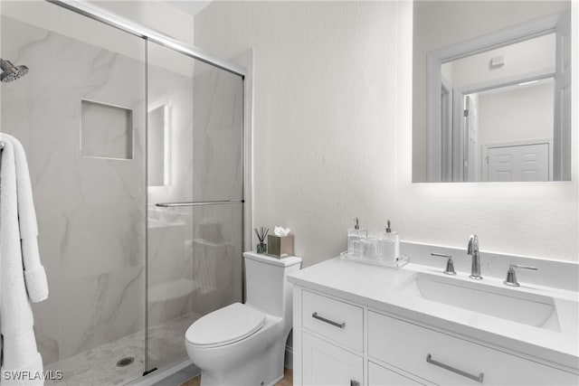 bathroom featuring vanity, toilet, and a shower with shower door