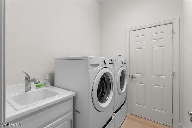 laundry area with washer and dryer, cabinets, sink, and light hardwood / wood-style flooring