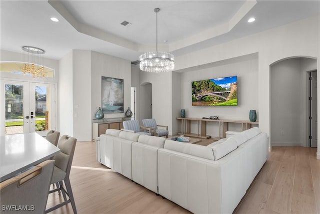 living room with french doors, light hardwood / wood-style floors, and a notable chandelier