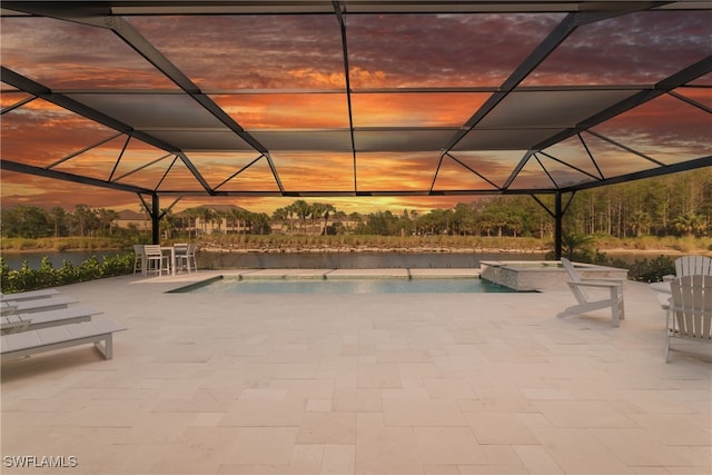 pool at dusk with glass enclosure and a patio