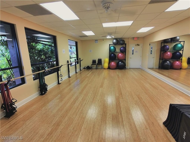 exercise area featuring light wood-type flooring and a drop ceiling