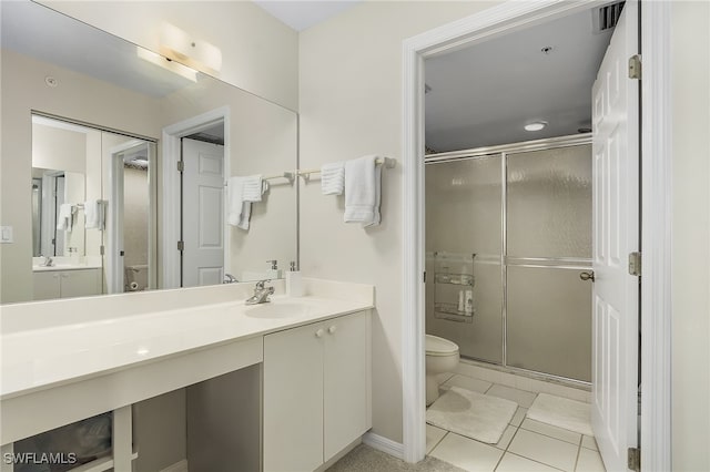 bathroom with tile patterned floors, toilet, an enclosed shower, and vanity