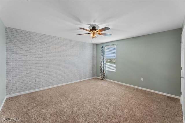 carpeted spare room with ceiling fan and brick wall