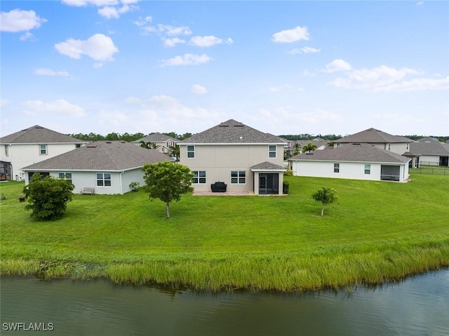 back of house with a lawn, a sunroom, and a water view