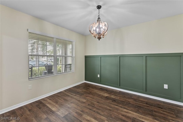 empty room featuring dark hardwood / wood-style flooring and an inviting chandelier