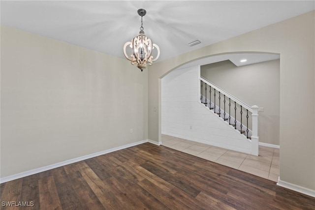 spare room with a chandelier and wood-type flooring