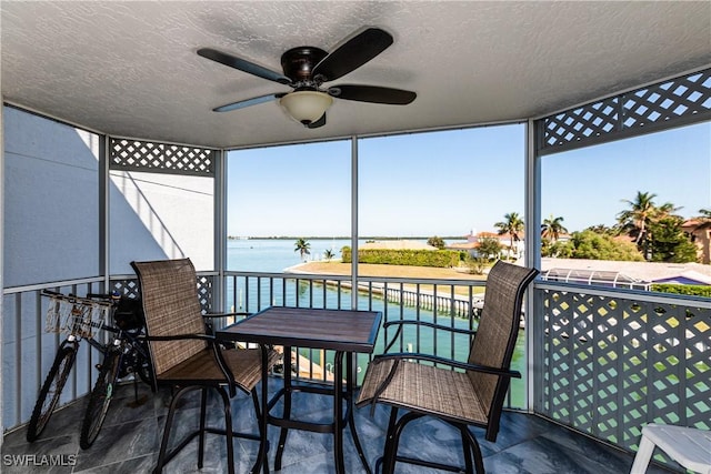 sunroom with a water view, ceiling fan, and a healthy amount of sunlight