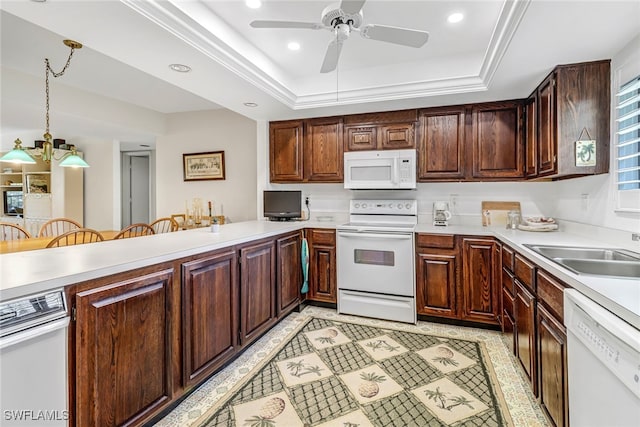 kitchen with kitchen peninsula, white appliances, a raised ceiling, sink, and decorative light fixtures