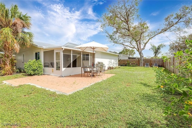 back of property with a lawn, a patio area, and a sunroom