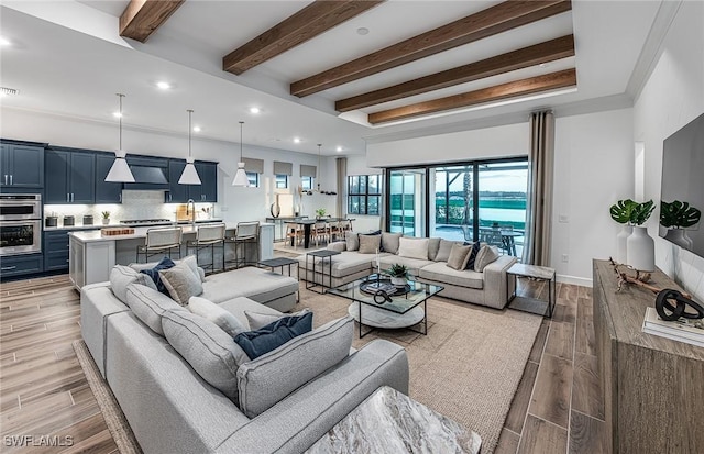 living room featuring beam ceiling, ornamental molding, sink, and light hardwood / wood-style flooring