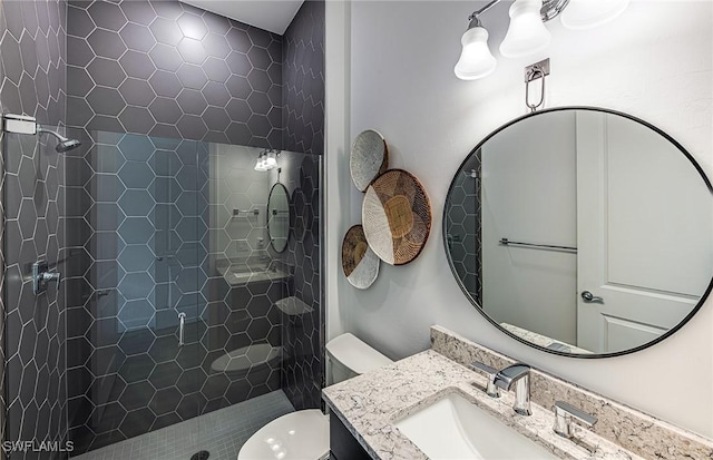 bathroom with tiled shower, vanity, and toilet