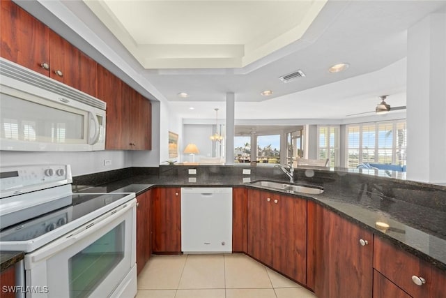 kitchen featuring white appliances, dark stone counters, ceiling fan with notable chandelier, sink, and light tile patterned flooring