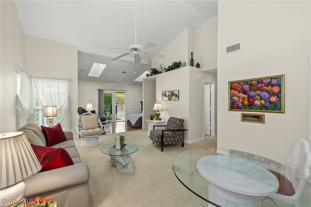 living room with a skylight, ceiling fan, french doors, high vaulted ceiling, and light colored carpet