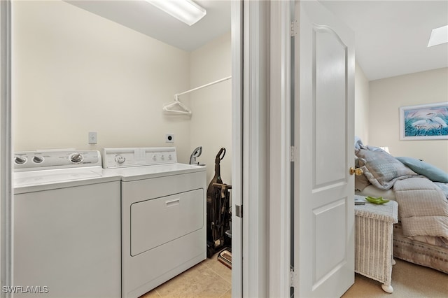 laundry room with washing machine and clothes dryer, a skylight, and light tile patterned floors