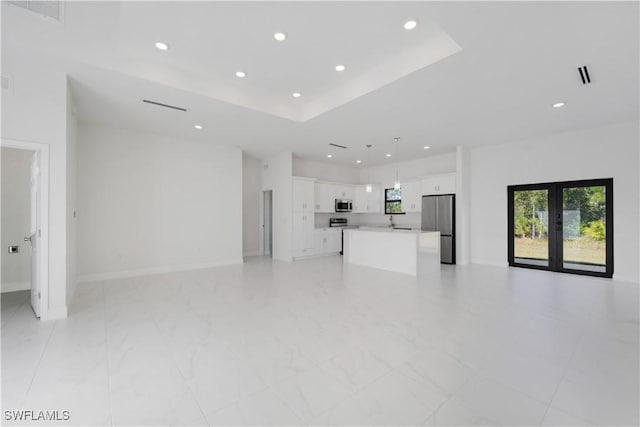 unfurnished living room with french doors, a raised ceiling, and sink