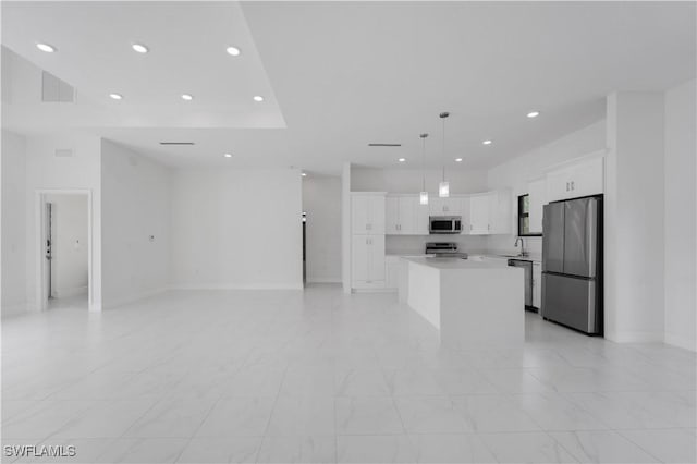 kitchen featuring sink, stainless steel appliances, a kitchen island, decorative light fixtures, and white cabinets