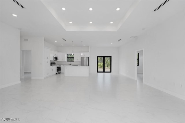 unfurnished living room featuring a raised ceiling and sink