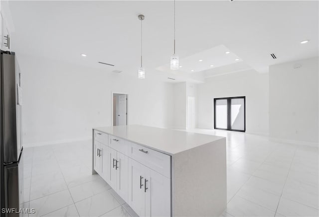 kitchen with white cabinetry, stainless steel fridge, a center island, and decorative light fixtures