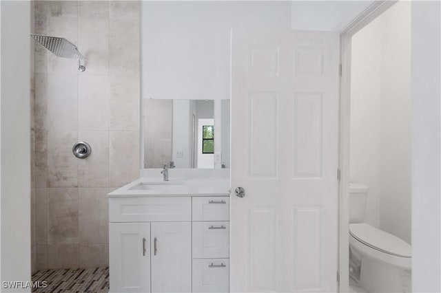 bathroom featuring vanity, toilet, and tiled shower