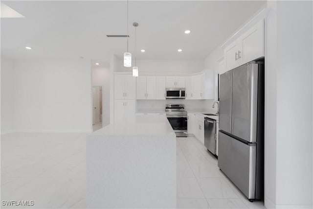 kitchen with white cabinets, sink, decorative light fixtures, a kitchen island, and stainless steel appliances