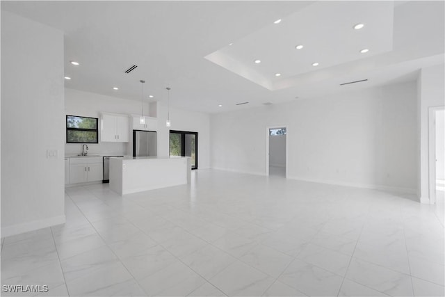 unfurnished living room featuring a raised ceiling and sink