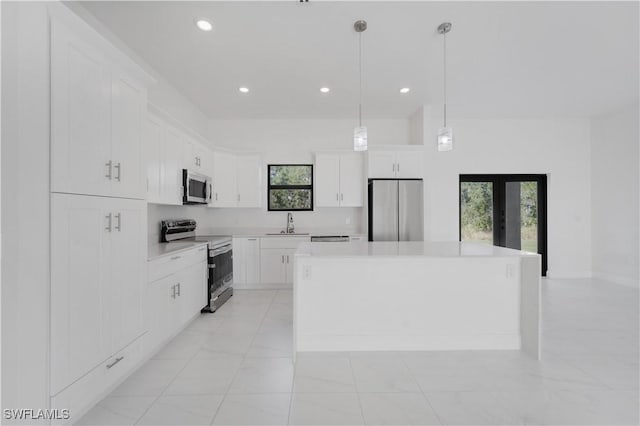 kitchen featuring a center island, hanging light fixtures, plenty of natural light, white cabinets, and appliances with stainless steel finishes