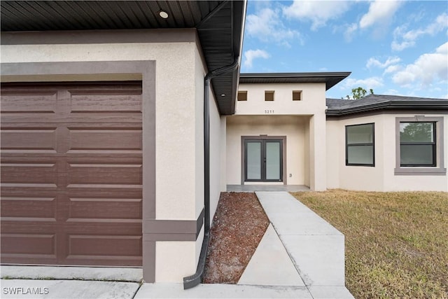 property entrance with french doors, a garage, and a lawn